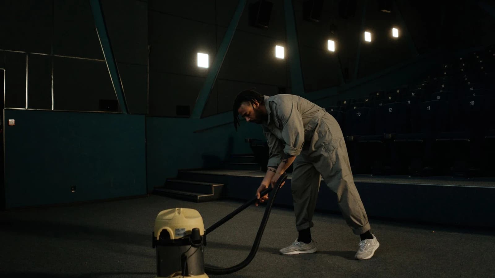 Commercial cleaner using a professional vacuum in an empty auditorium